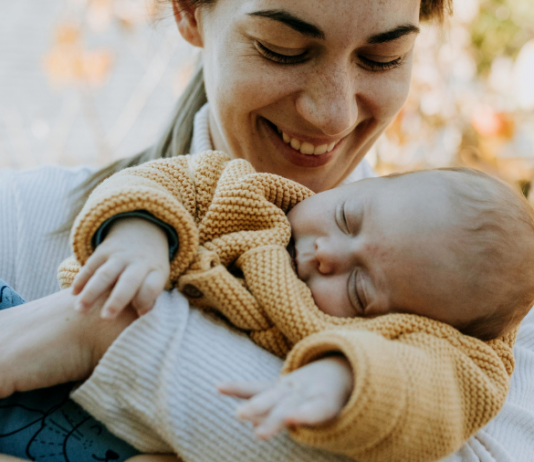 Mama ist draußen und hat ihr Baby im Arm