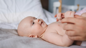 Baby liegt beim Wickeln auf einem Bett