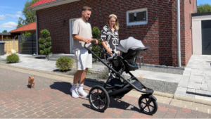 Mama, Papa und Kind machen Spaziergang mit dem Kinderwagen