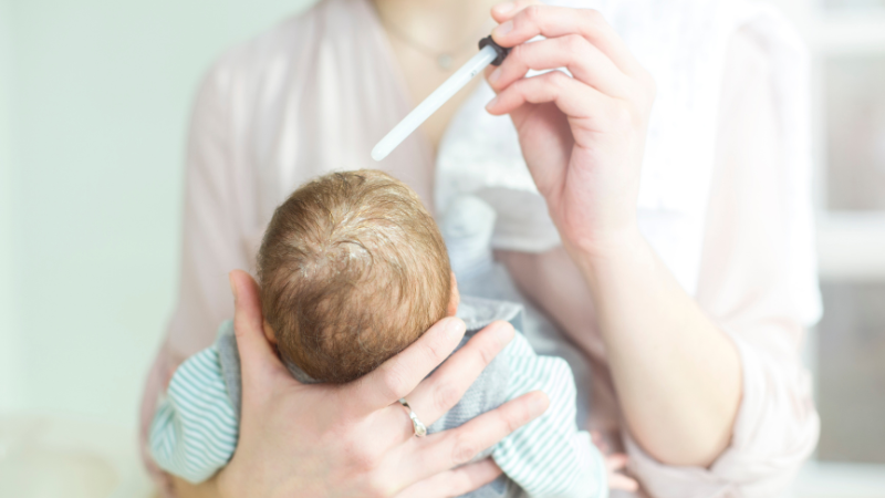 Mutter behandelt den vom Milchschorf befallenen Kopf ihres Babys.