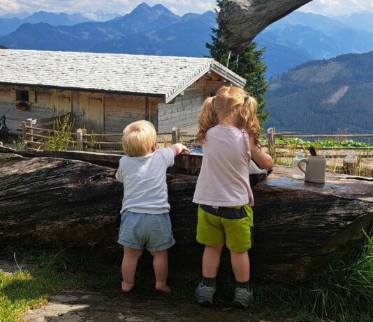 Zwei Kinder spielen an einem Brunnen