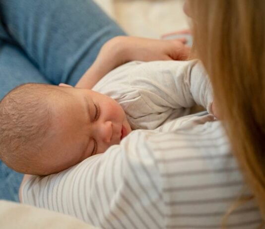 Mama hält schlafendes Baby im Arm